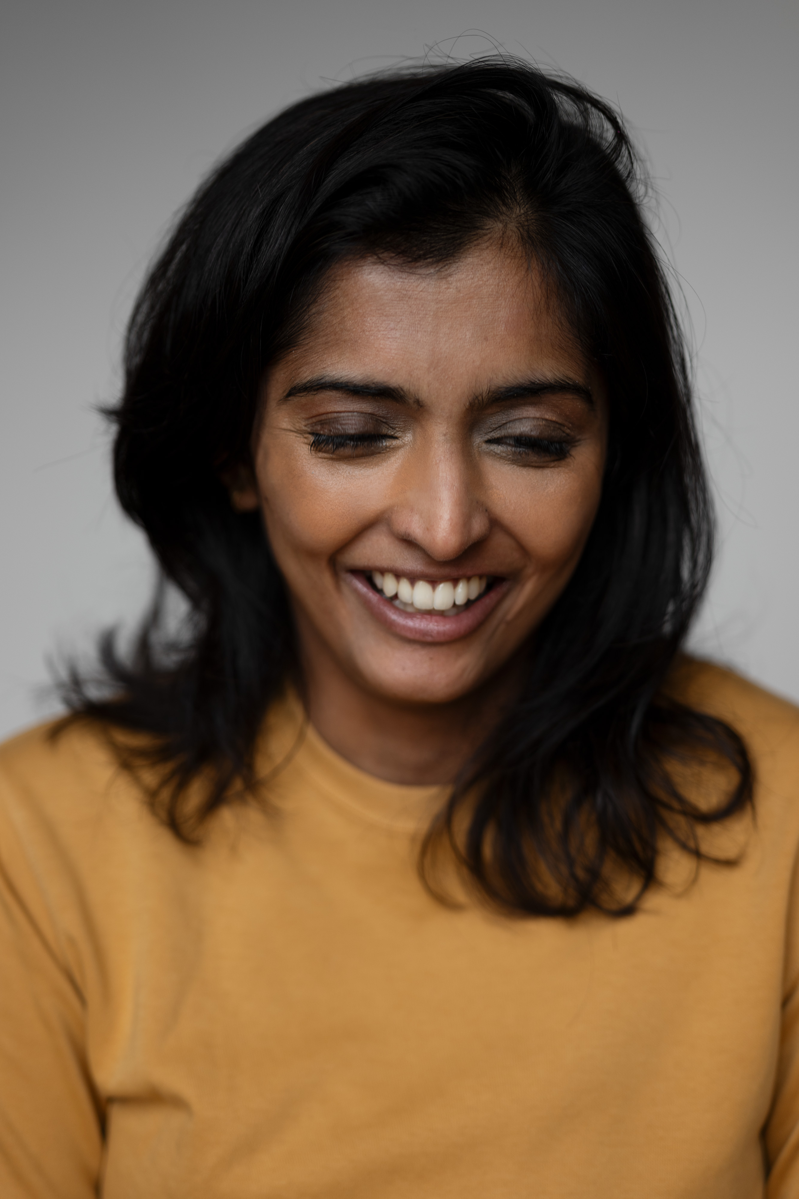 Portrait of Komal Amin smiling in a mustard top.